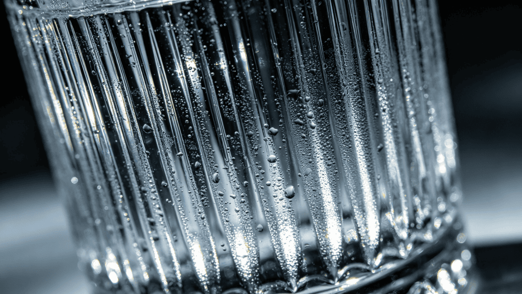 Close-up of a ribbed clear glass tumbler with water droplets, highlighting its vertical ridges and reflective surface